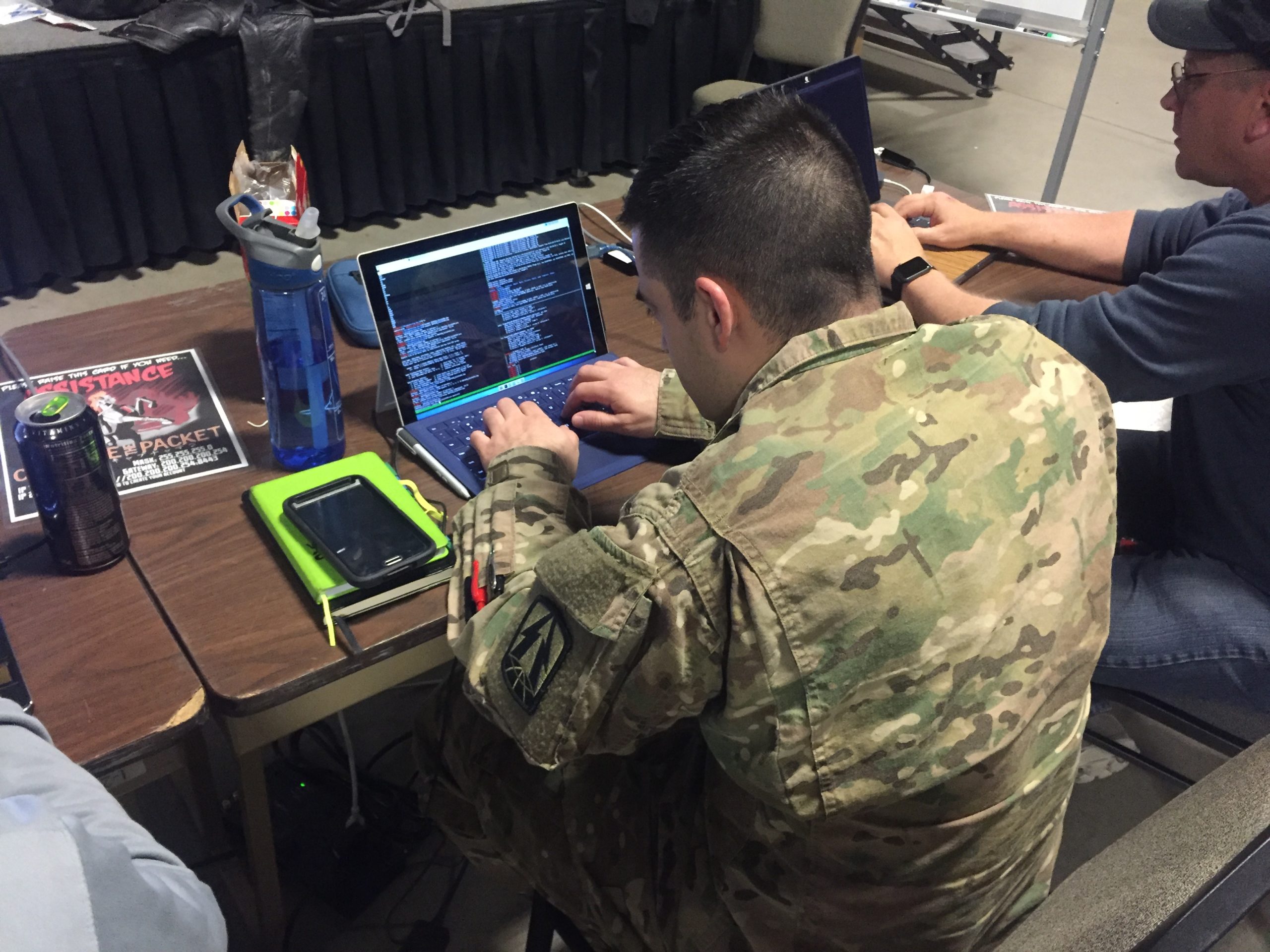 A soldier using a laptop to edit code.